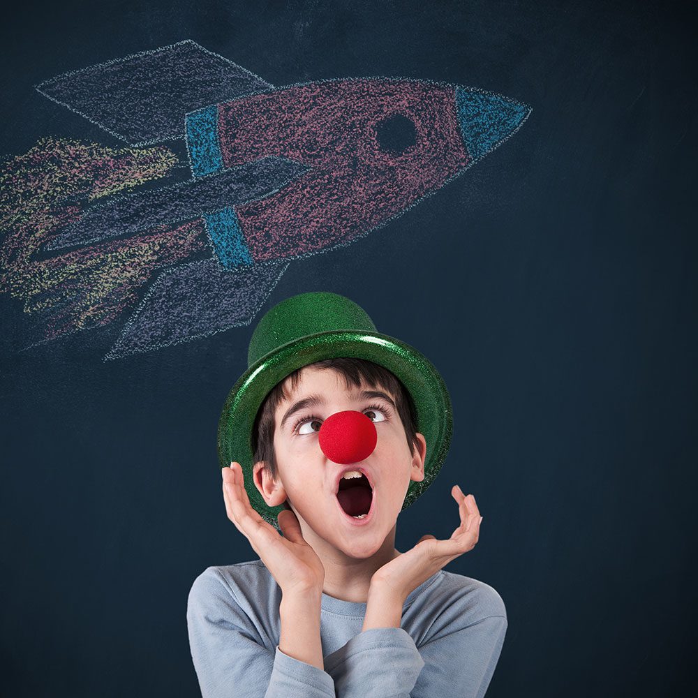 A boy with a clown nose and hat singing.