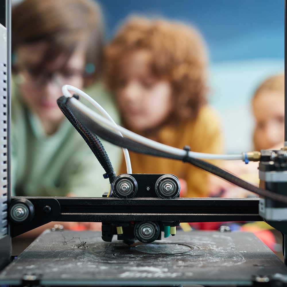 Three children working with a 3D printer.