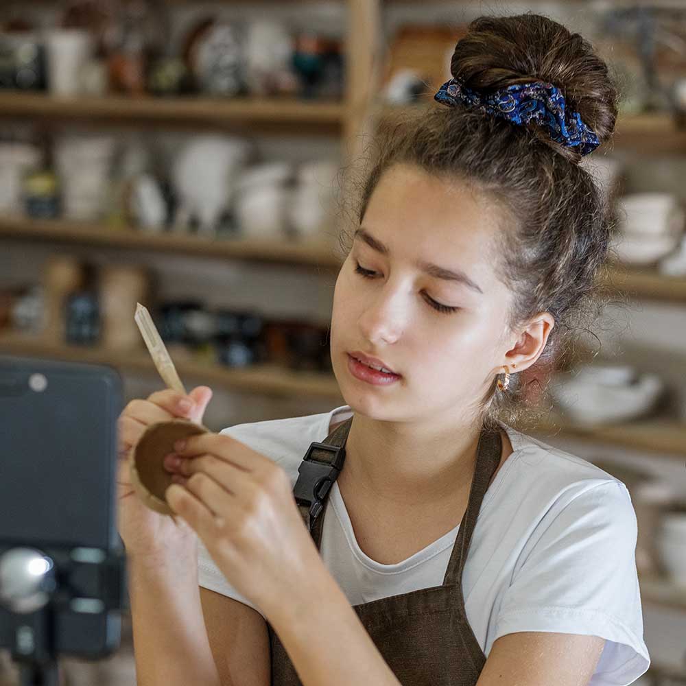 Teen sculpting with clay in a studio.